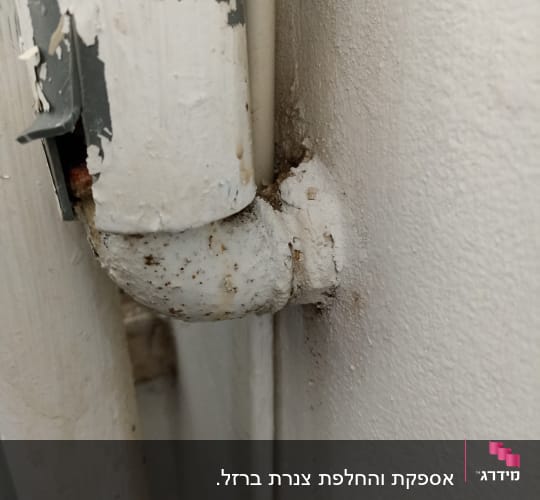 צינור מתכת חלוד עם חיבור לקיר
